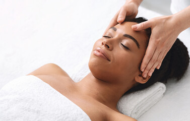 High angle view of black lady having relaxing head massage at spa salon, copy space © Prostock-studio
