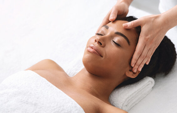 High angle view of black lady having relaxing head massage at spa salon, copy space