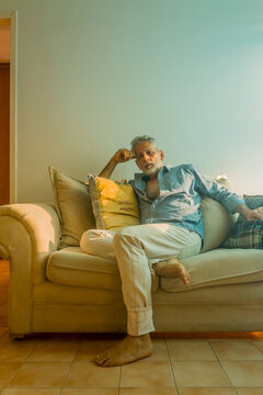 Stylish mature man with silver hair relaxing on a sofa in a bright living room