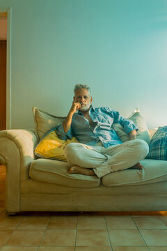 Stylish mature man with silver hair relaxing on a sofa in a bright living room