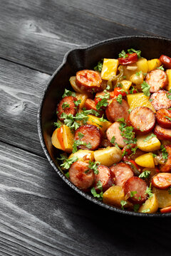 Roasted Potato and Sausage in frying pan on dark wooden table