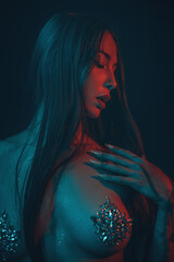 Young beautiful woman artistic topless portrait in dark colors with red light