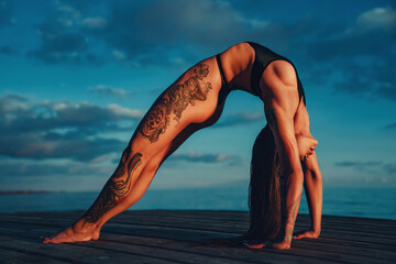 Young slim beautiful woman sports stretching on lake shore on summer day, tattoo on body