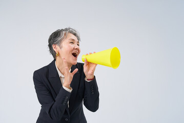 応援のポーズをするスーツ姿のシニア女性