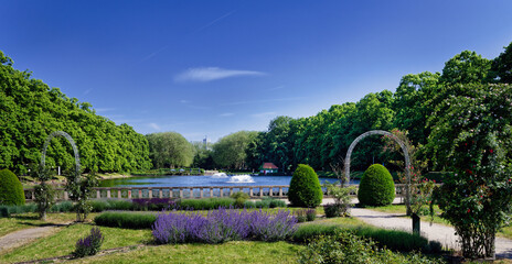 Symmetrical garden design in Cologne's Bluecherpark featuring a pond, fountains, and lavender blooms under a blue sky. Historic landmark park, Germany. © gehapromo