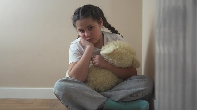Young girl sitting on the floor. Lifestyle child is punished by girl in a corner. A teenager is upset by the violence of a domestic. A little girl seated on the ground.