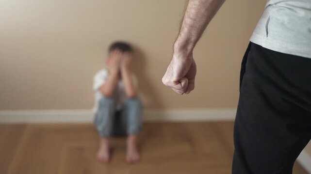 Man is holding child's hand. A child is fisting at a parent. Family members fear violence lifestyle in the corner. A man is grasping a child's hand.