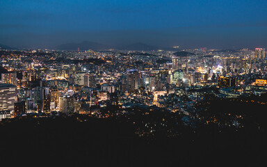 Fototapeta premium Seoul night skyline, South Korea, beautiful aerial twilight view, with mountains and scenery beyond the city, seen from observation deck of Namsan Park, Gyeonggi-do province, Republic of Korea