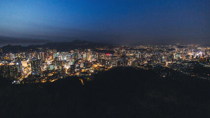 Fototapeta premium Seoul night skyline, South Korea, beautiful aerial twilight view, with mountains and scenery beyond the city, seen from observation deck of Namsan Park, Gyeonggi-do province, Republic of Korea