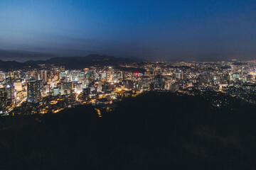 Fototapeta premium Seoul night skyline, South Korea, beautiful aerial twilight view, with mountains and scenery beyond the city, seen from observation deck of Namsan Park, Gyeonggi-do province, Republic of Korea