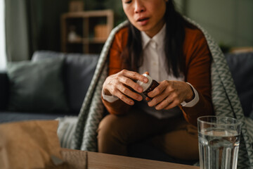 Sick woman taking medication at home feeling unwell