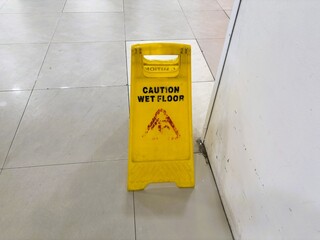Yellow warning sign on a ceramic tile floor.