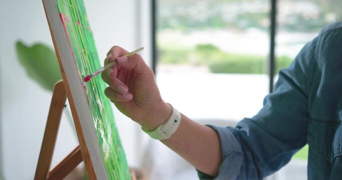 Artist is touching canvas edge with pink paint near window, applying strokes to define left border