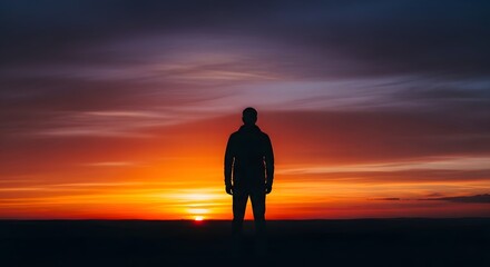 Fototapeta premium Human Silhouette & Anonymous People. A man stands alone in silhouette against a vibrant sunset