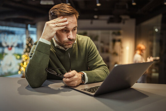 Stressed businessman feeling frustrated working on laptop in office
