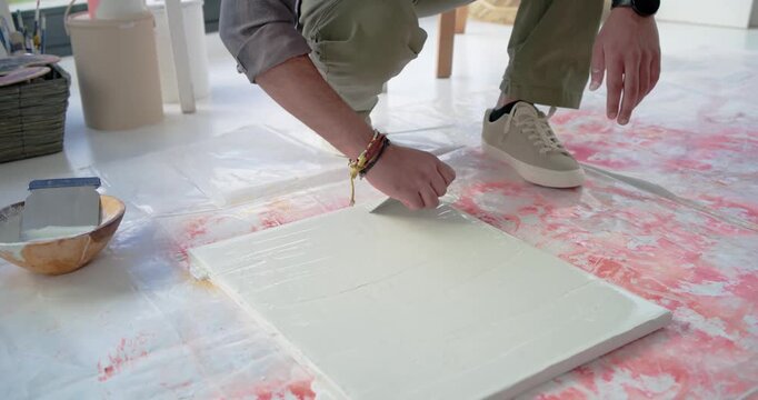 Artist is stepping and tooling canvas with notched comb by door, making arched ridges