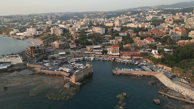 Ascending drone video showcases picturesque panorama of Byblos at sunset.