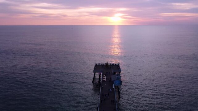 Circling Christmas Tree with a Star on top with Beautiful Pink Sunset at the San Clemente Pier in Southern California. Seasonal festive holiday decorations outdoors in public.