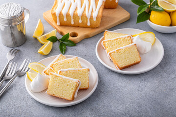Lemon pound cake with sugar frosting sliced on plates served with whipped cream