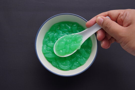 Hand holding spoon with green pandan jelly. cendol indonesian food