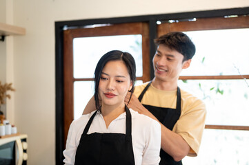 Obraz premium Asian couple a man tying woman or girlfriend's hair before cooking a food while standing in kitchen.
