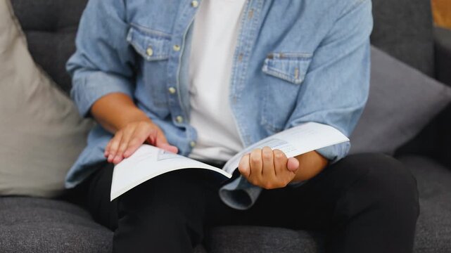 Asian Person in Denim Shirt Reading and Flipping Pages of a Booklet