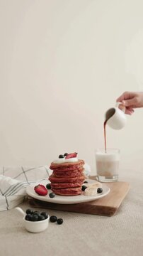 pouring Syrup into Glass of Milk with Pink Beetroot Pancakes Stack
