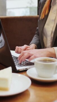 Businesswoman working on laptop in cafe with coffee and cheesecake