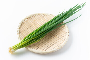 白背景に竹笊に載せた小ねぎ（万能ねぎ）