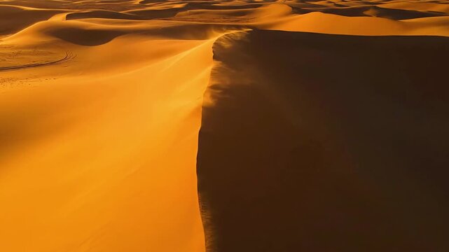 Vast golden sand dunes in desert landscape with wind blowing dust during sunset