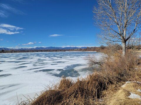 Late winter frozen Sloan's lake (Colorado), with clear blue skies and rocky mountains in the background