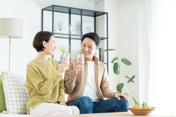 リビングでミネラルウォーターを飲むミドルの夫婦