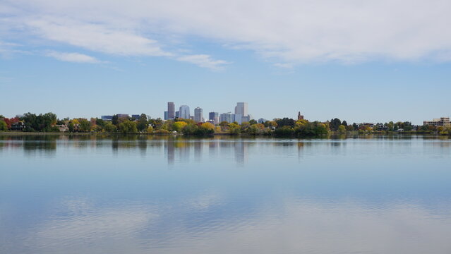 Summer clear waters of Sloan's lake(Colorado), vibrant vegetation, cloudy blue skies and few Central Downtown Denver Skyscrappers
