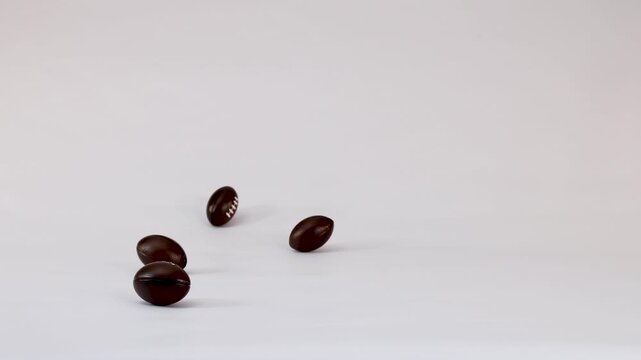 Miniature Chocolate Footballs Falling and Bouncing on a White Background