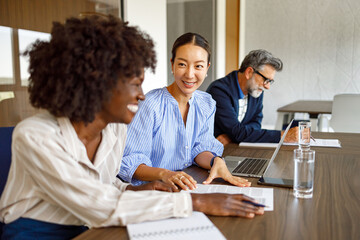 Fototapeta premium Female accountants discussing financial reports during professional meeting in modern boardroom with businessman in the background