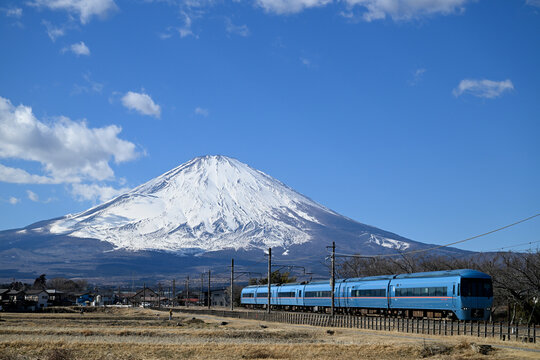 Scenic view of a modern train traveling through the countryside with snow-capped Mount Fuji in the background. Iconic Japanese landscape combining transportation and nature, ideal for travel and touri