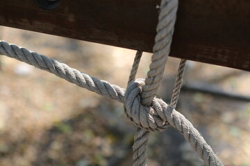 Close-up of a sturdy knot made with thick rope secured to a wooden beam