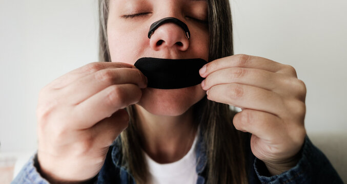 Latina woman using nasal strip and mouth tape for better sleep and breathing - Biohacking and wellness concept