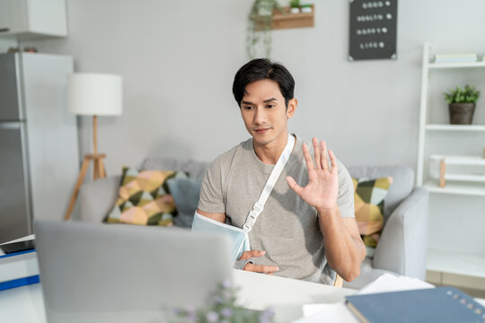 Injured Asian businessman wearing hand splint while working from home