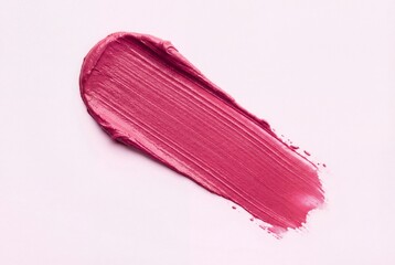 Vibrant pink creamy makeup texture smear isolated on a clean light pink background