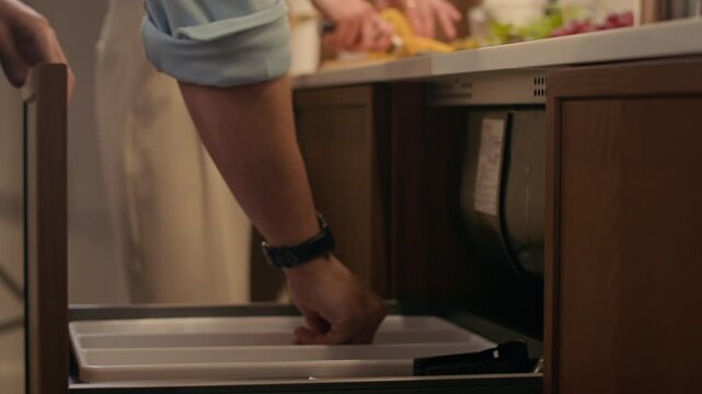 Handheld shot of unrecognizable couple in elegant clothes helping each other while preparing home dinner together with fruits, vegetables, salad and white wine