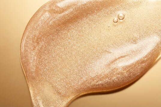 Luxurious shimmering gold cosmetic gel smear with viscous texture and bubbles