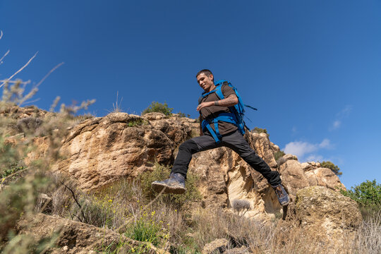 Adventurer man jumping over rocky mountain terrain