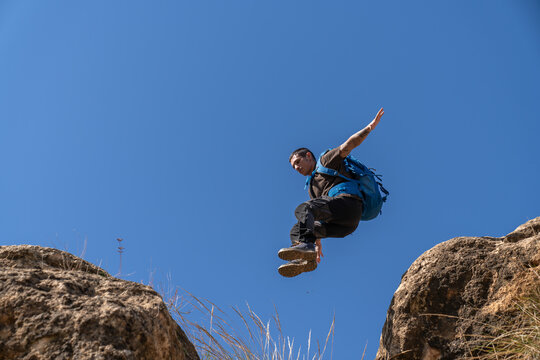 Man jumping cliff gap outdoor adventure challenge