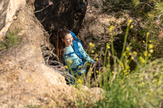 Woman with backpack hiking up rocky mountain path