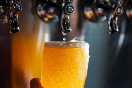 Overflowing glass of beer just poured from tap