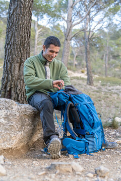 Hiker organizing backpack on trail during outdoor adventure
