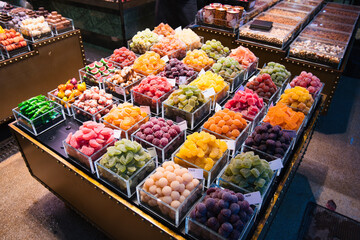 Obraz premium Assorted vibrant candies, jellies, and nuts filling clear containers, creating an inviting, abundant display at a lively food market, appealing to sweet cravings and culinary exploration