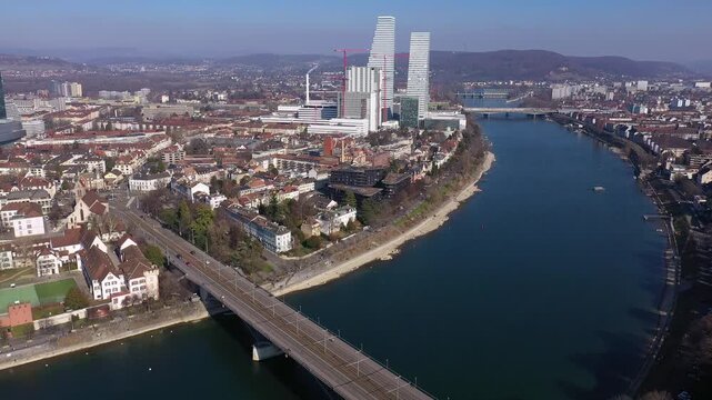 Basel, Switzerland: Aerial drone footage of the Rhine that flow through the medieval Basel old town with a tramway crossing the bridge with modern office tower in Switzerland