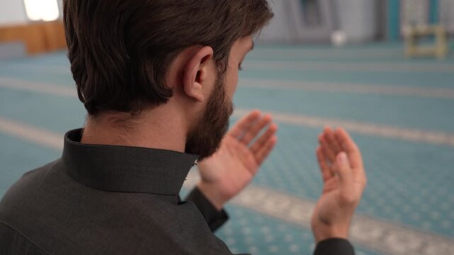 Muslim male making Dua and praying in a mosque with a rosary. Young Muslim man supplicating during Ramadan at masjid. Spiritual Islamic worship and devotion concept with a Sheikh.
